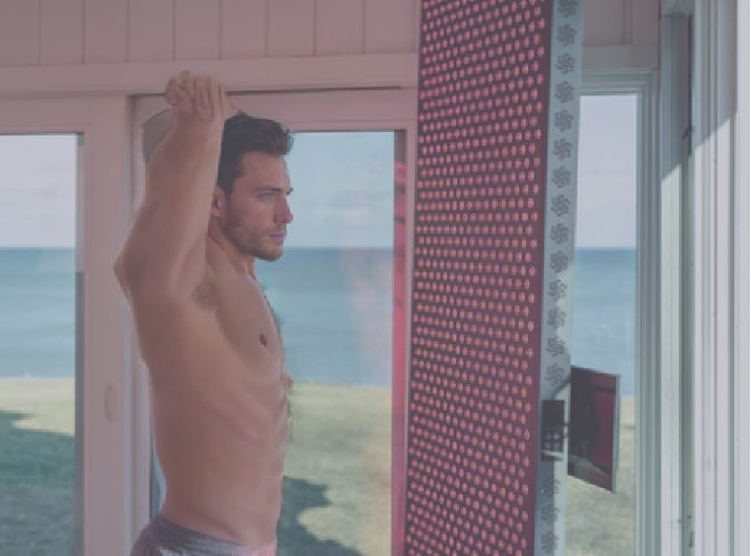 man stretches in front of full body red light device