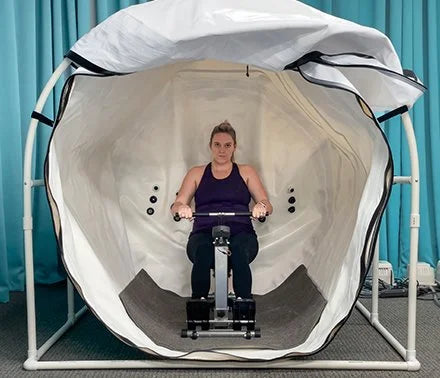Woman using a rowing machine inside the Summit to Sea Grand Dive Pro Plus